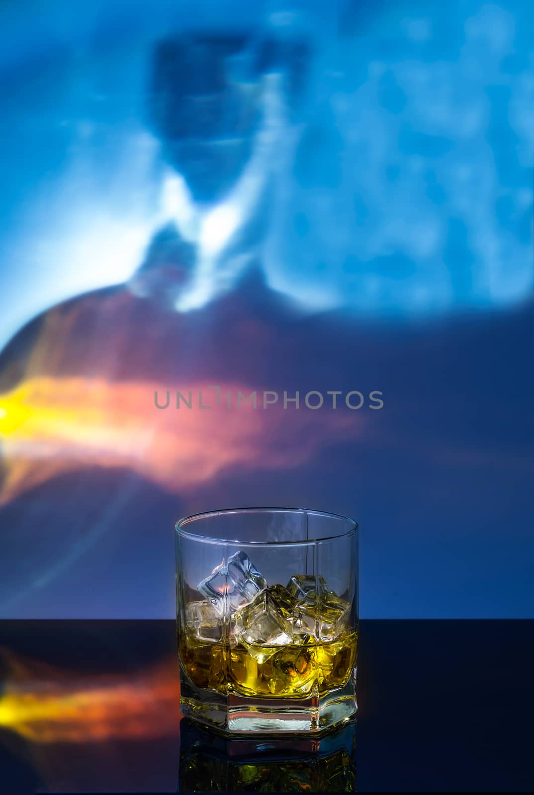 a glass of whiskey with ice on a black polished table