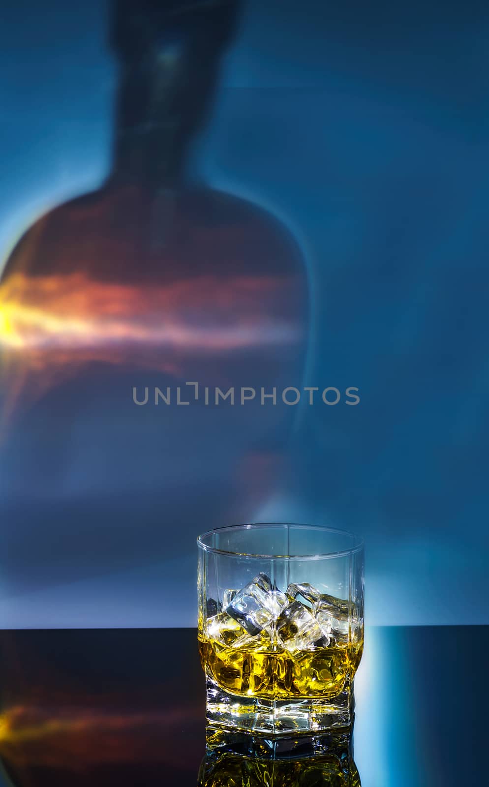 a glass of whiskey with ice on a black polished table