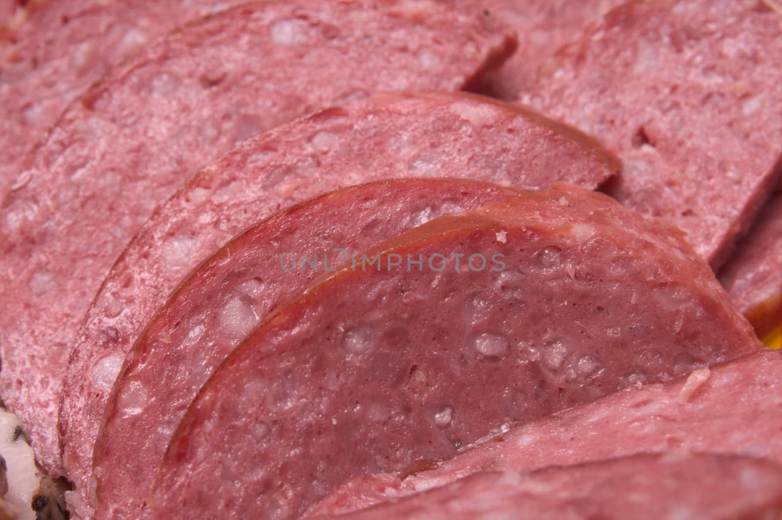 Closeup for few red round salami slices sausages with small pieces of fat in it