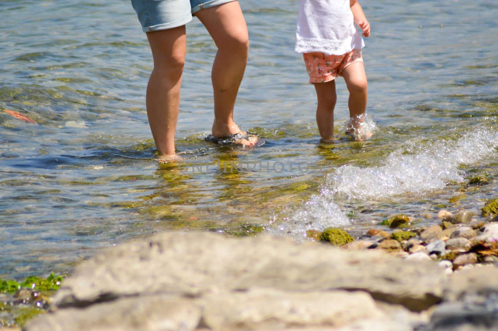 Legs of a mother and daughter in the water of the Garda Lake in Italy