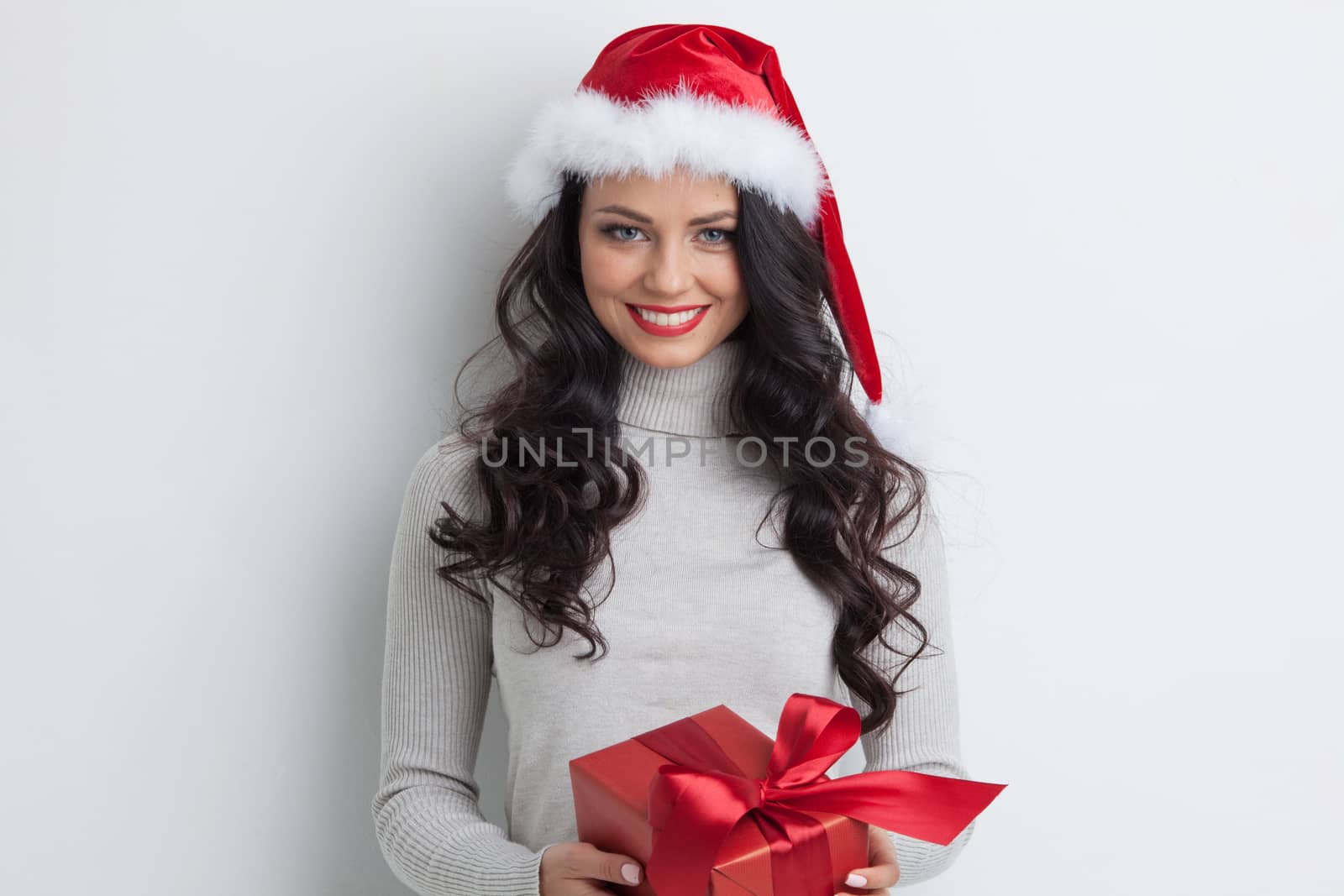 Young woman in Santa hat hug her Christmas gift