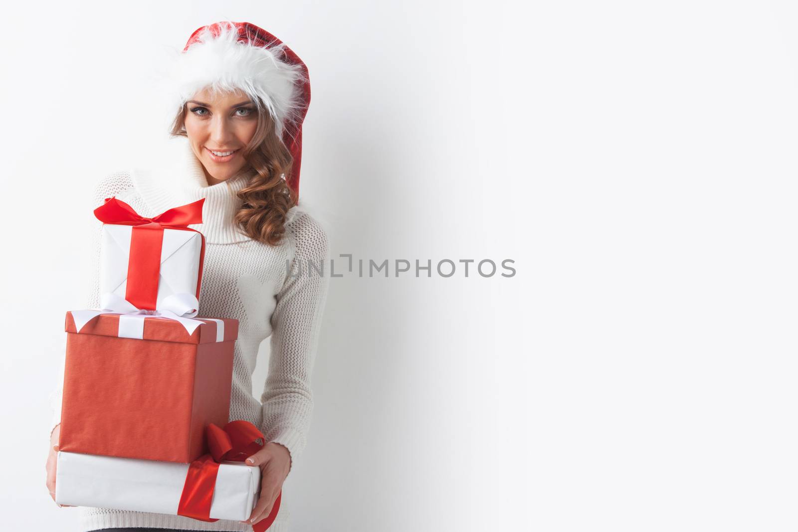 Young woman in Santa hat holding her Christmas gifts