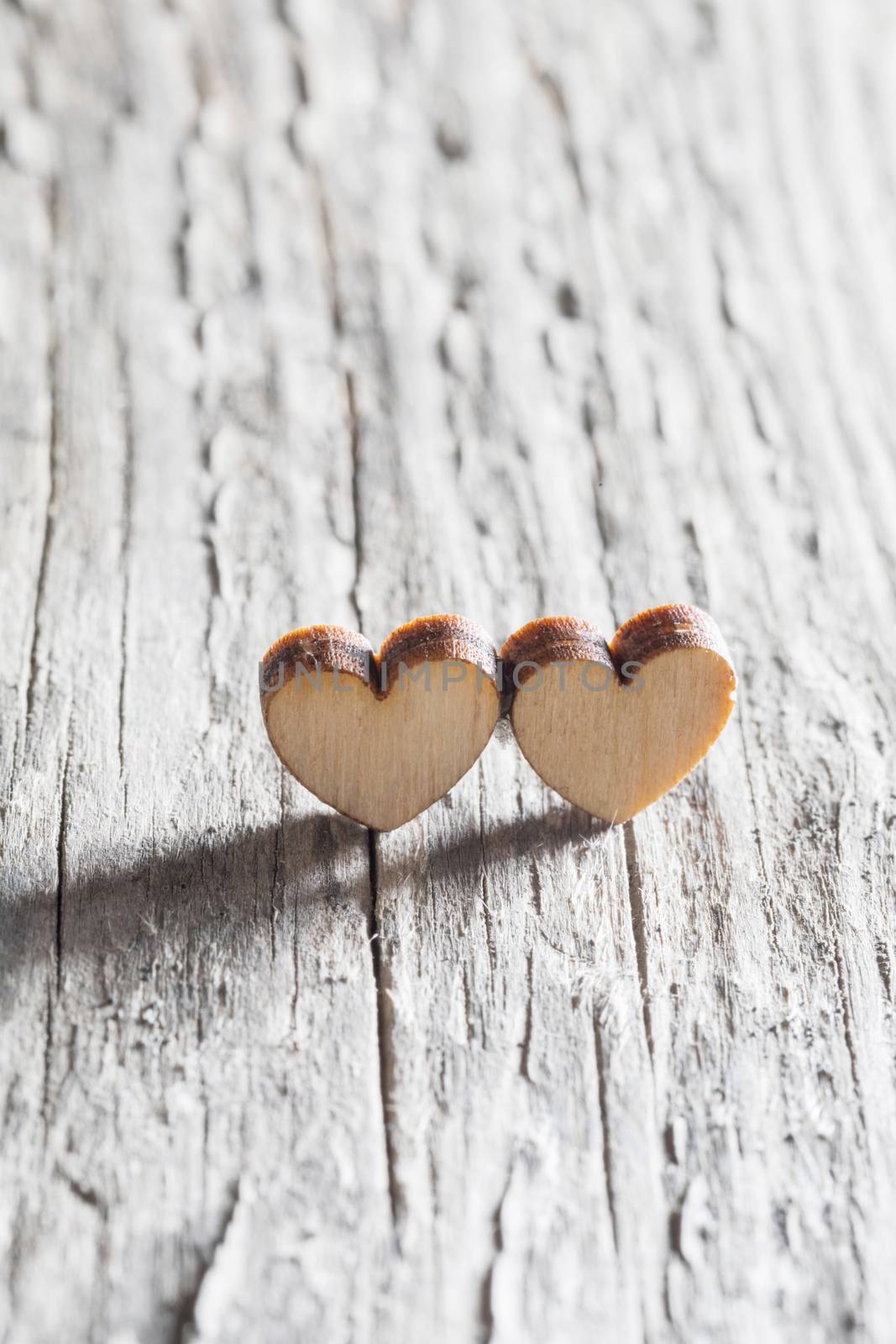 Two small wooden hearts on old cracked wood background