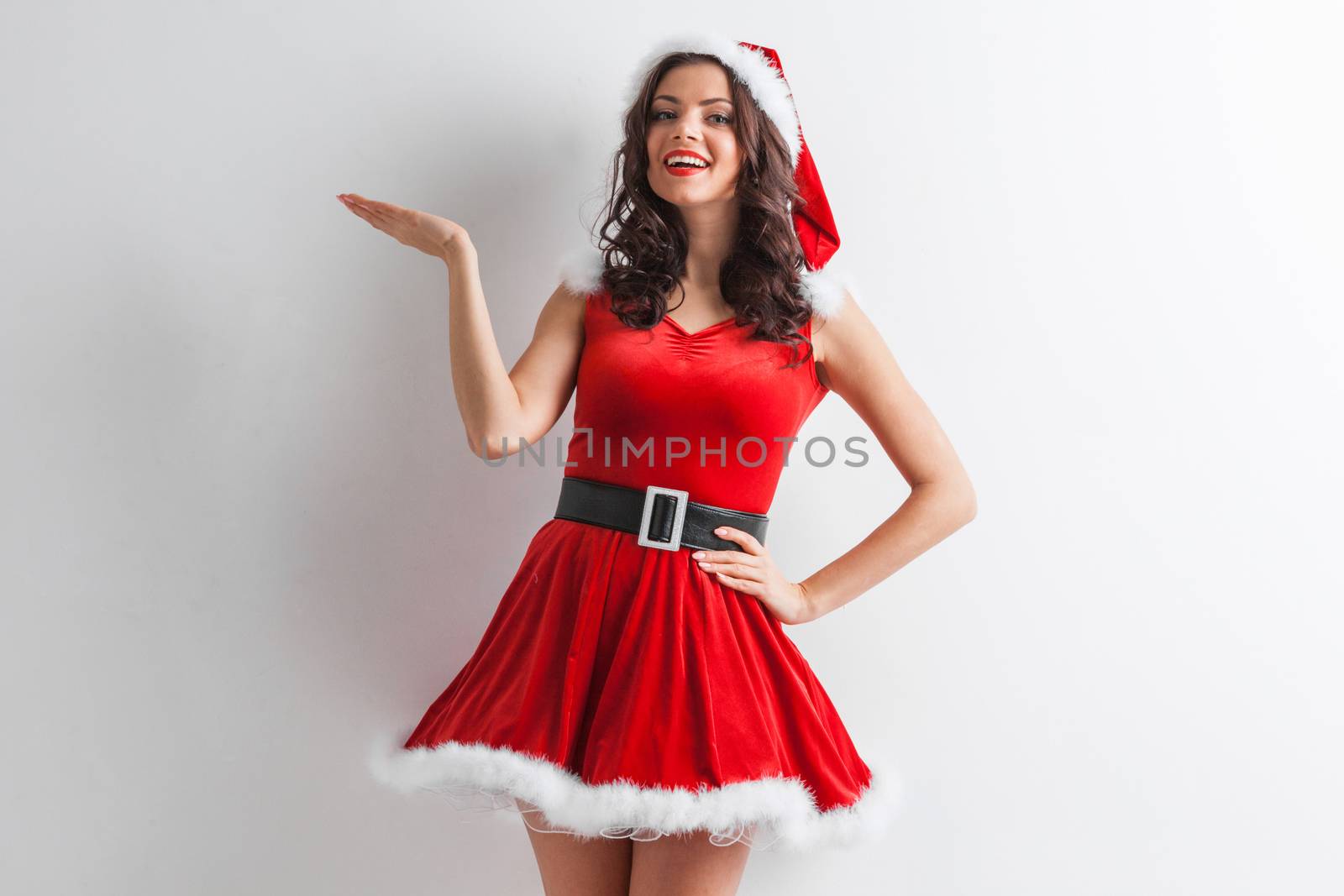 Young brunette christmas girl holding something on white background, copy space for text