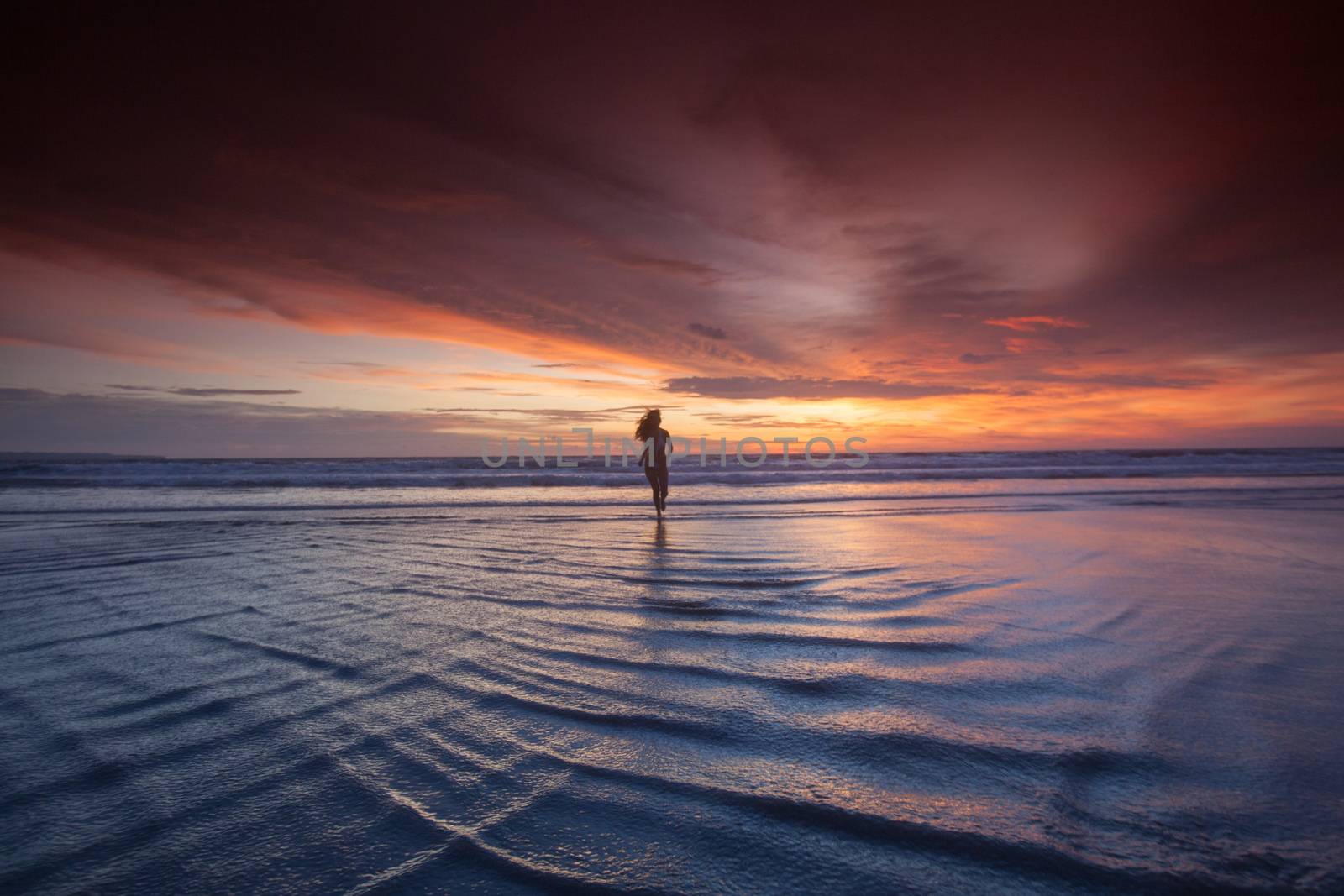 Woman in bikini running on the beach at sunset. Bali island, Indonesia