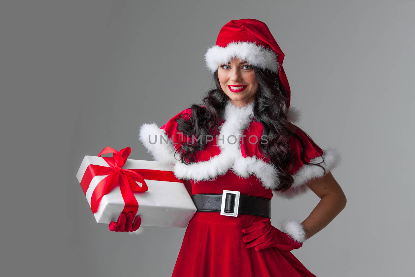 Woman in red Santa Claus outfit holding christmas gift box