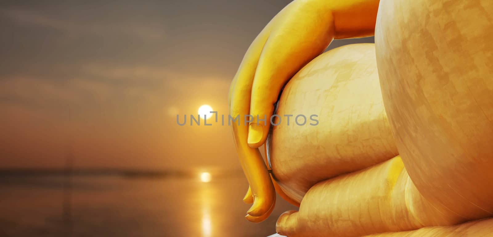 Hand of golden buddha statue and sitting at sunset.