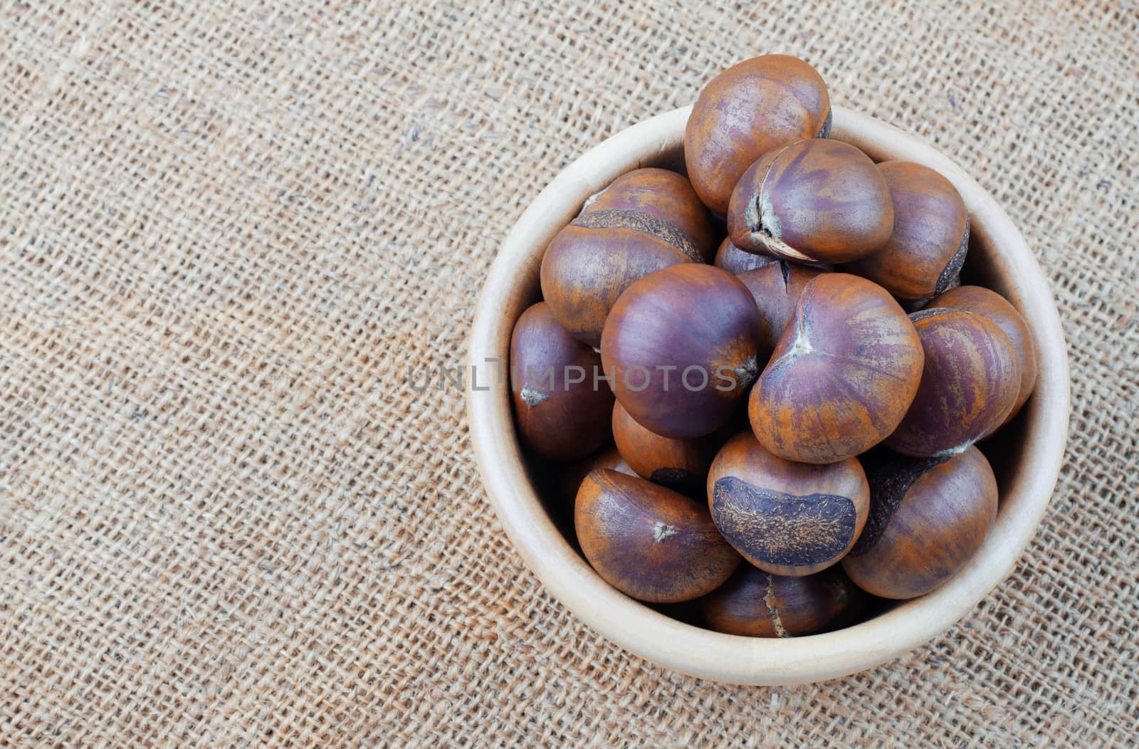 Chestnuts in a wooden bowl on sack.