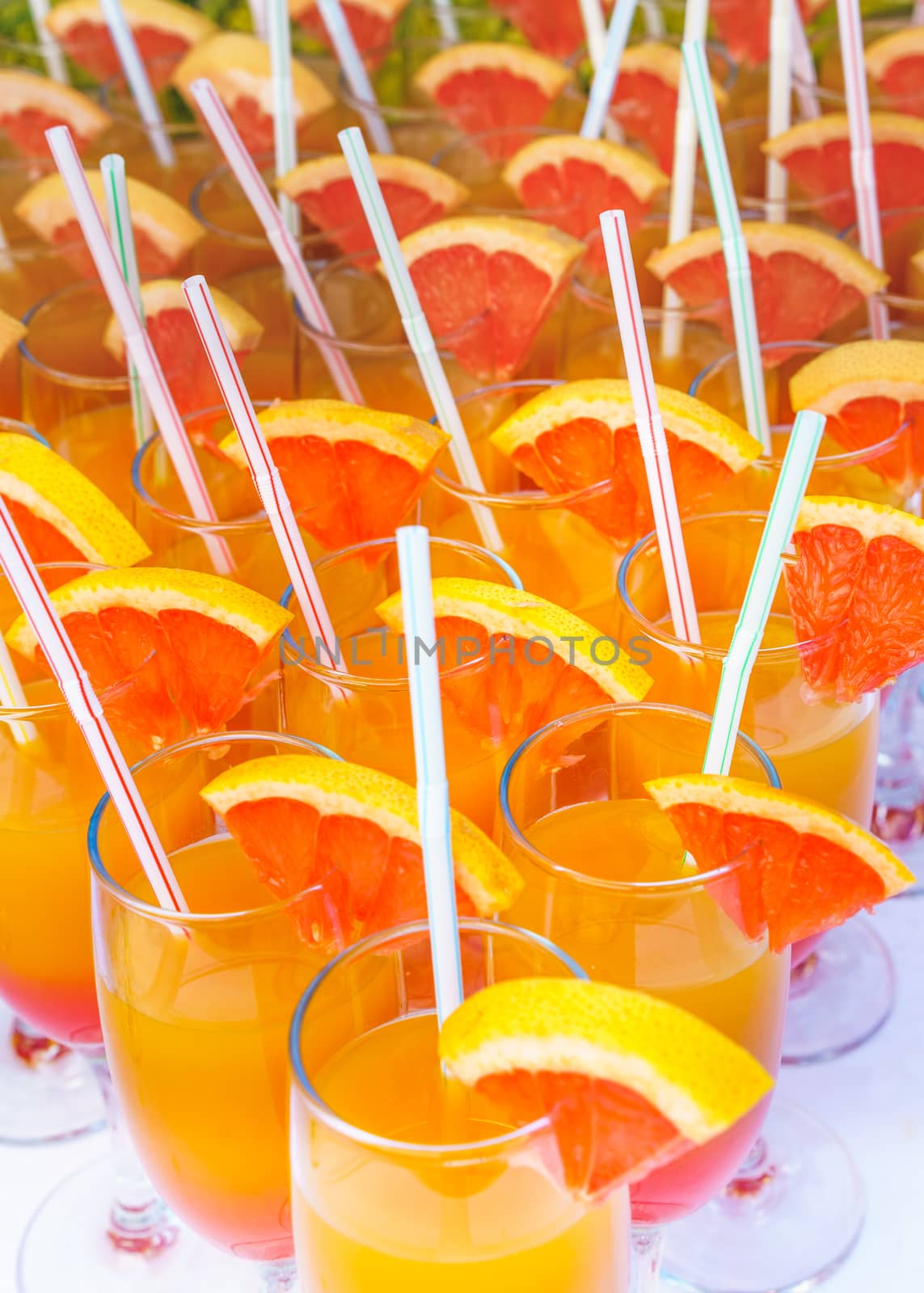 Orange juice cocktail in a flute glasses and slice of fresh orange with draw on white table,closed picture.