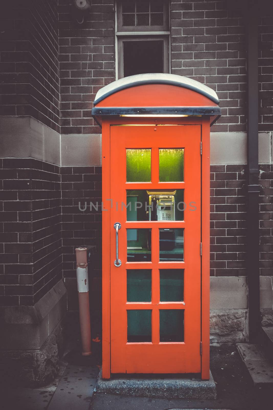 Vintage UK red phone booth in front of a brick wall