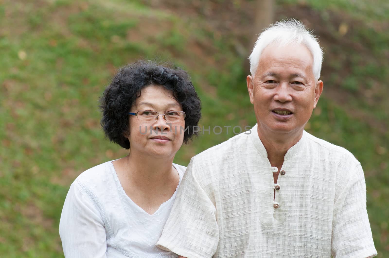 Happy Asian senior couple relaxing at outdoor park on a summer day.