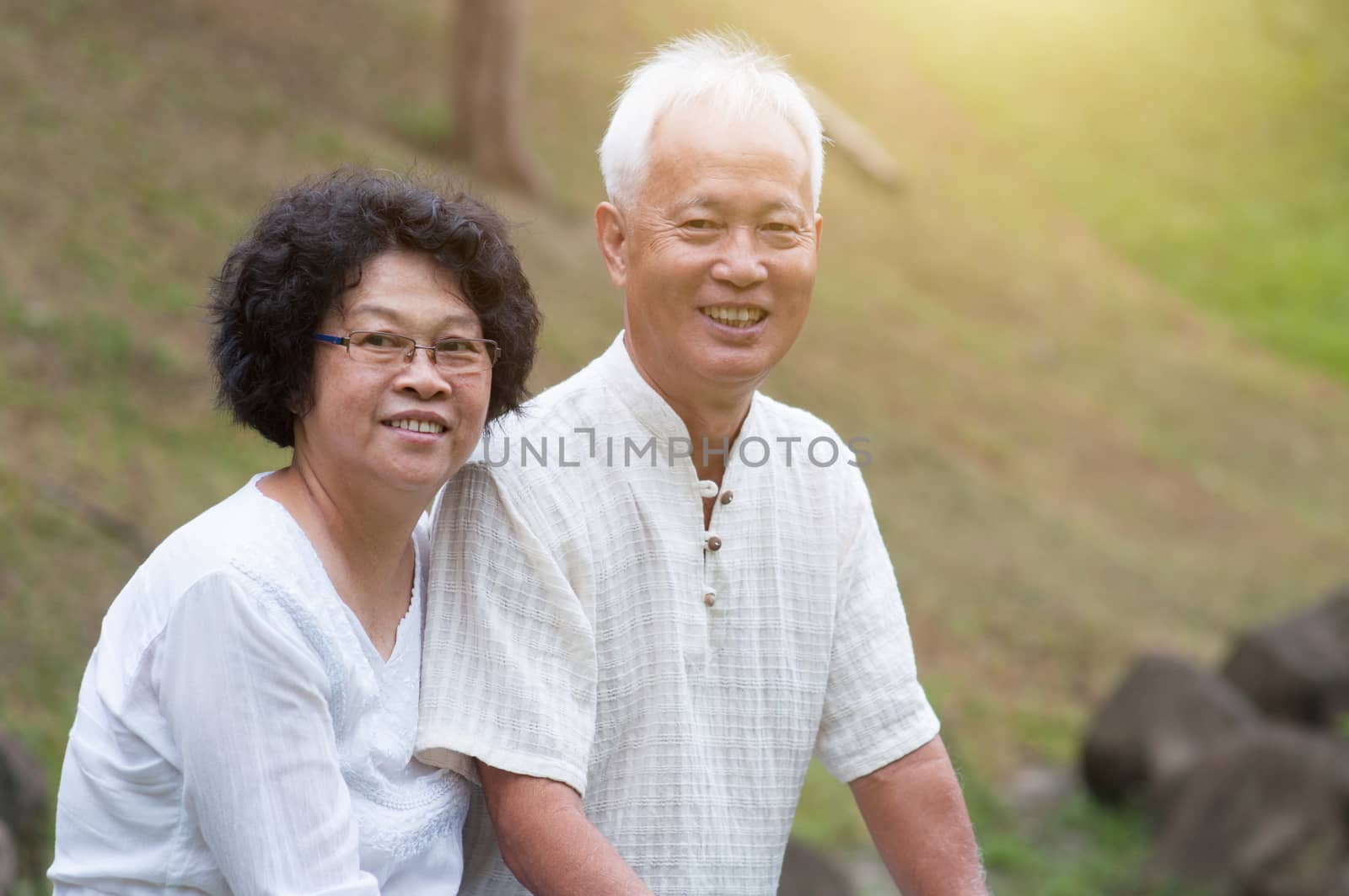Happy Asian elderly couple relaxing at outdoor park on a summer day.