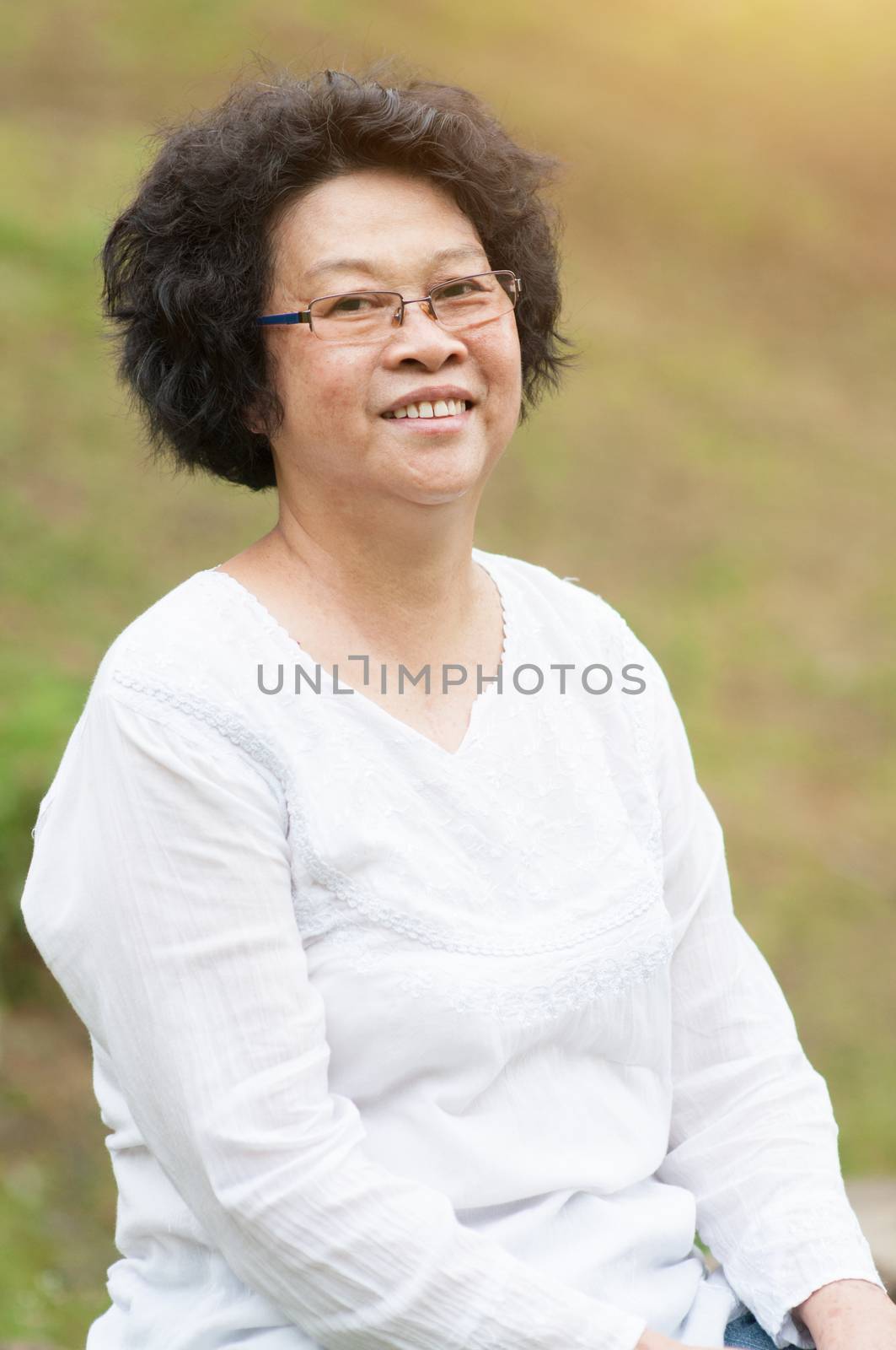 Happy Asian mature woman relaxing at outdoor park.