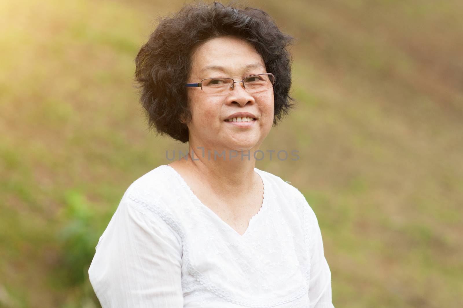 Happy Asian elderly woman relaxing at outdoor park.