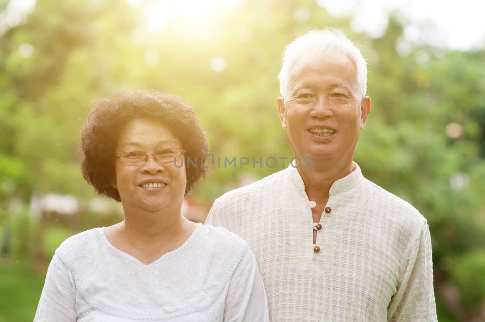 Happy Asian elderly couple smiling at outdoor park.