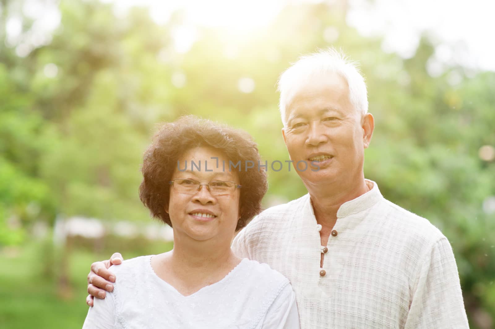 Happy Asian old couple smiling at outdoor park on a sunny day.