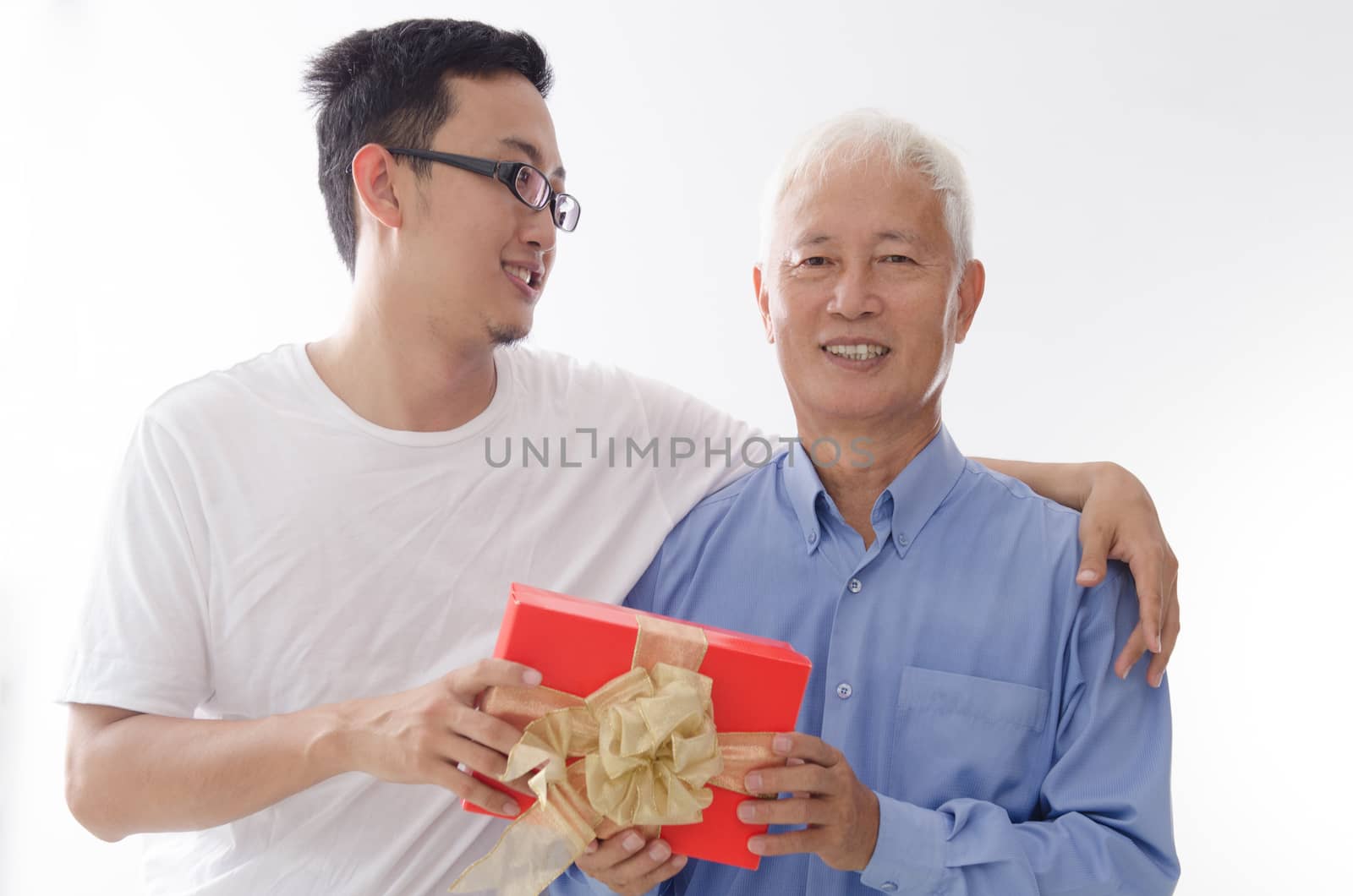 Asian elderly father and son hand holding a present and smiling,  standing isolated on white background.