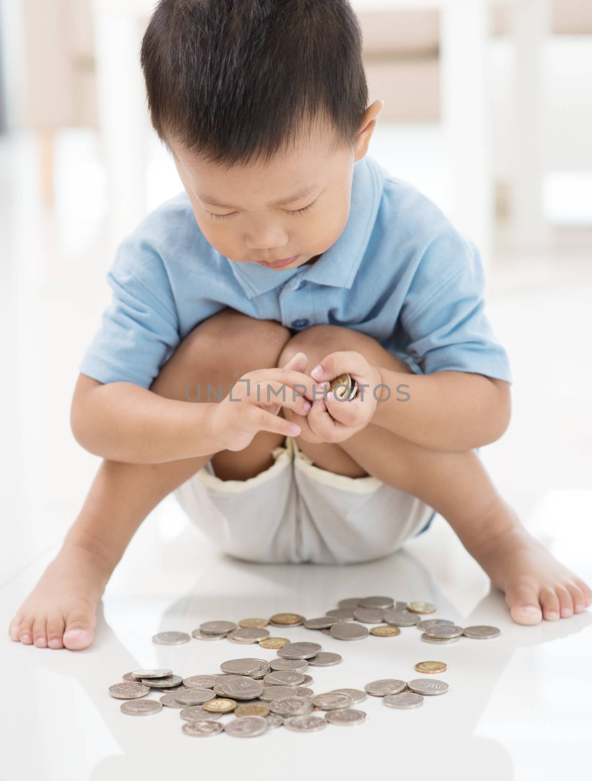 Asian boy saving coins at home. Child education fund concept. 