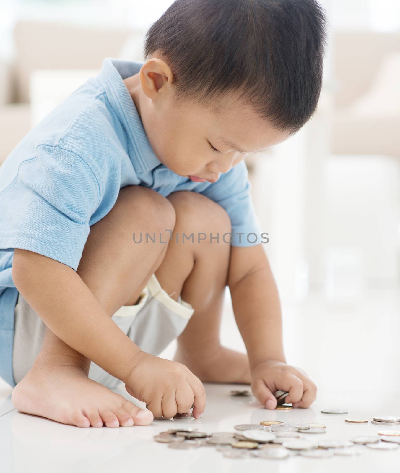 Asian boy saving coins at home. Child future educational fund concept. 