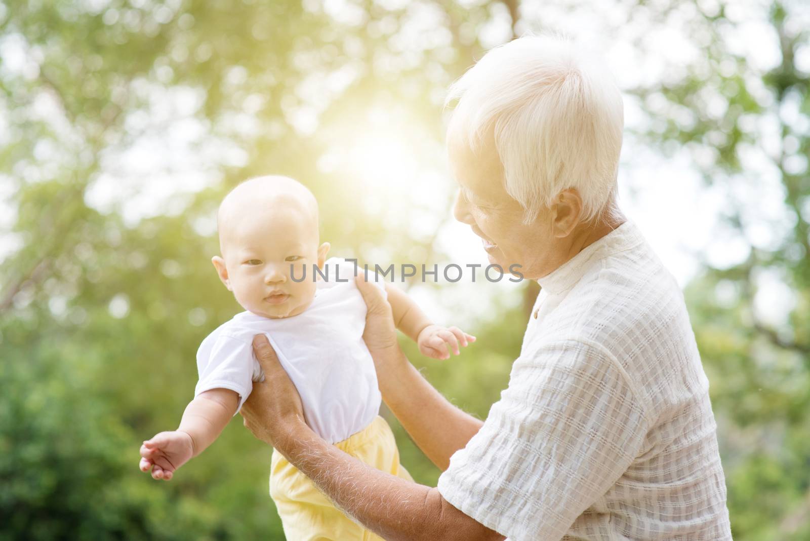 Happy grandfather with baby grandchild at outdoors park. Asian family, life insurance concept.
