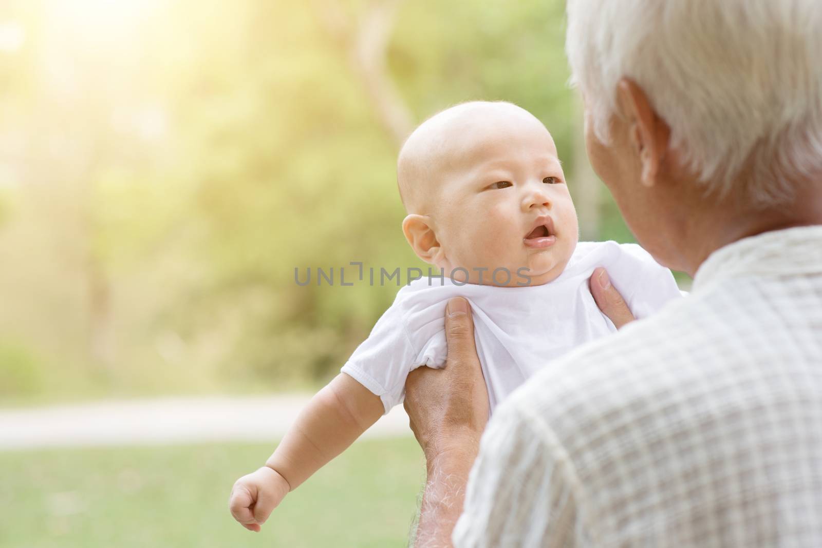 Happy grandfather with baby grandson at outdoors park. Asian family, life insurance concept.