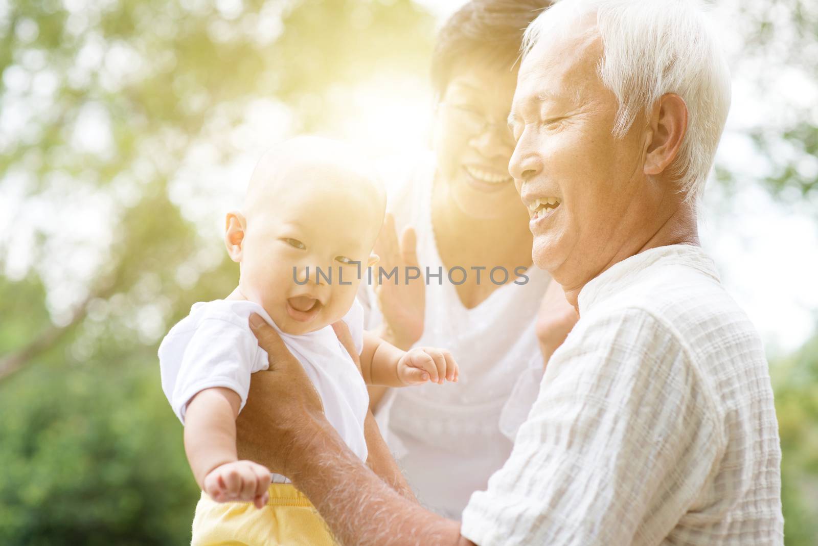 Happy grandparents playing with their grandson at outdoor park, Asian family, life insurance concept.