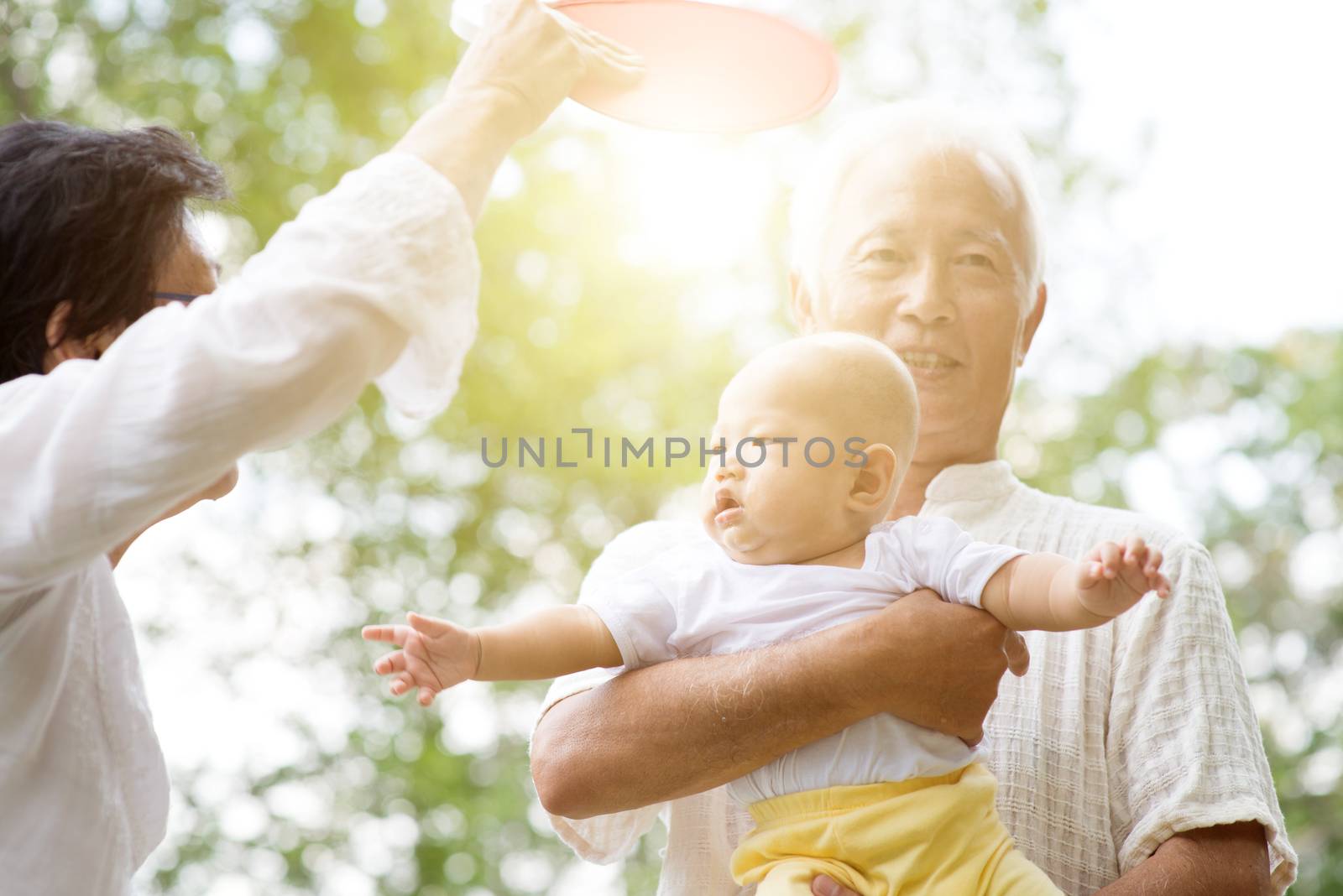 Grandparents taking care of baby grandchild in outdoor park. Asian family, life insurance concept.