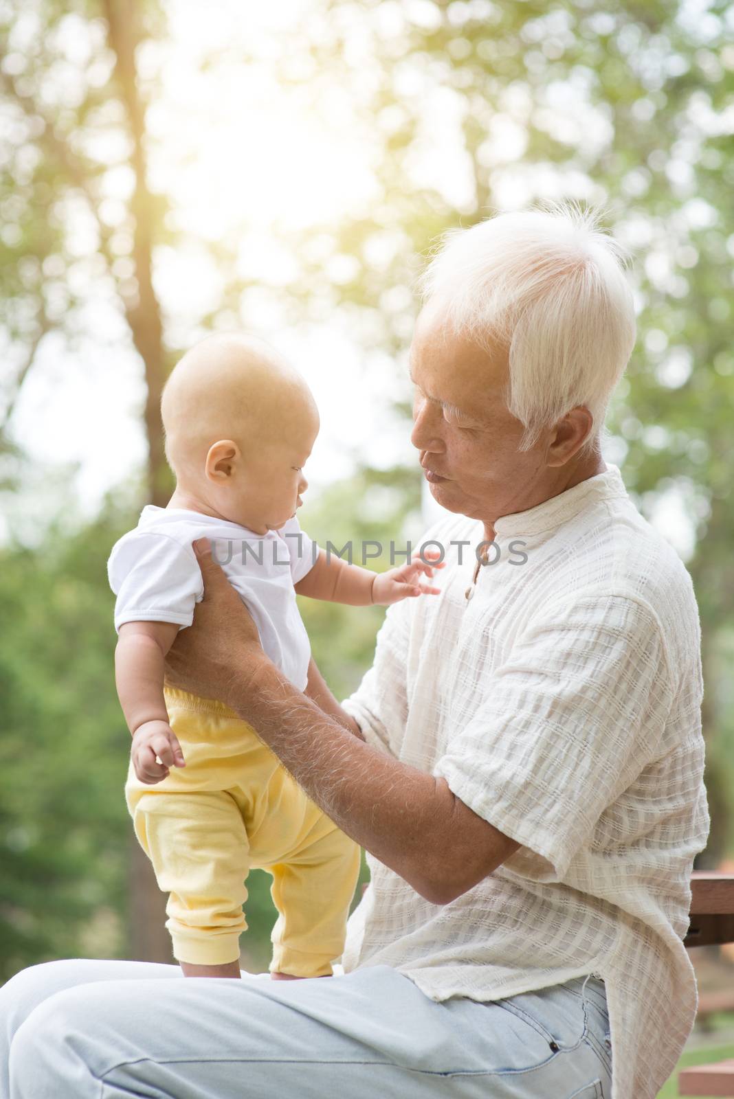 Grandfather holding grandson at outdoor bench. by szefei