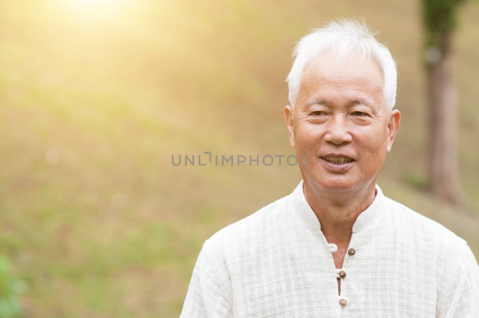 Happy Asian elderly man relaxing at outdoor park.