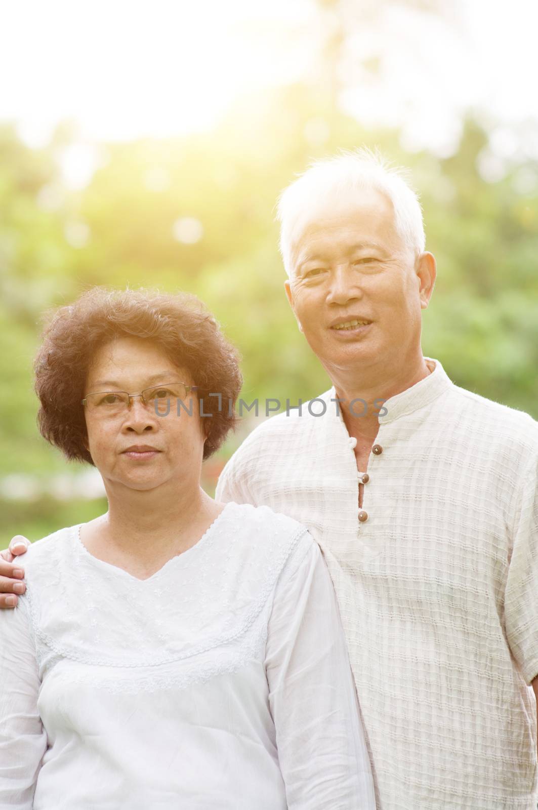 Happy Asian mature couple smiling at outdoor park on a sunny day.