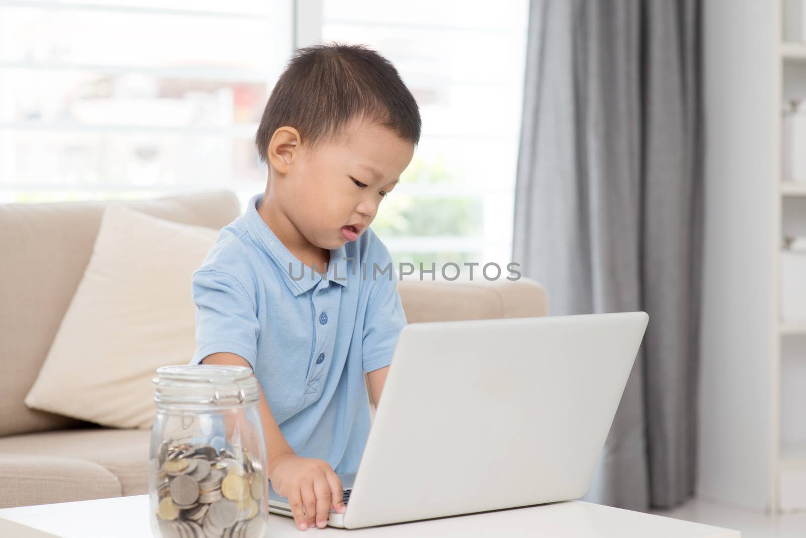 Asian preschool boy using computer laptop at home. Child education and technology concept. 