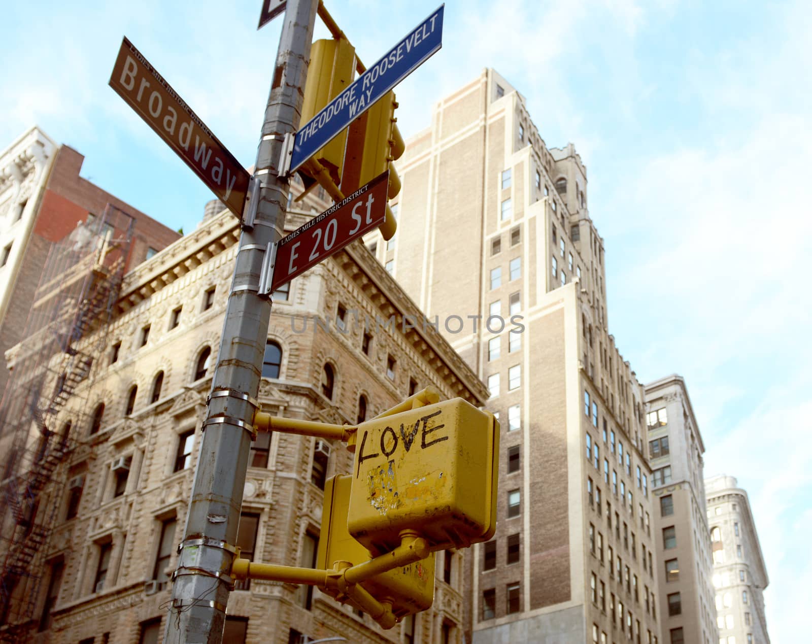 Street signs at the corner of East 20th Street and Broadway, with crossing light graffitied with the word LOVE