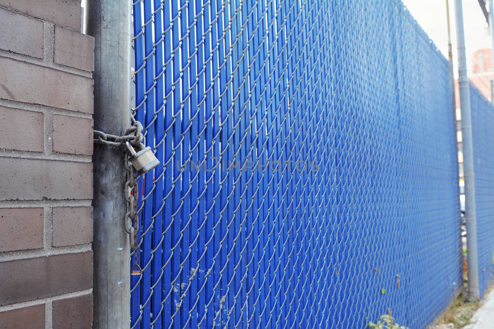 Blue plastic and metal security fence and gate secured with a heavy padlock