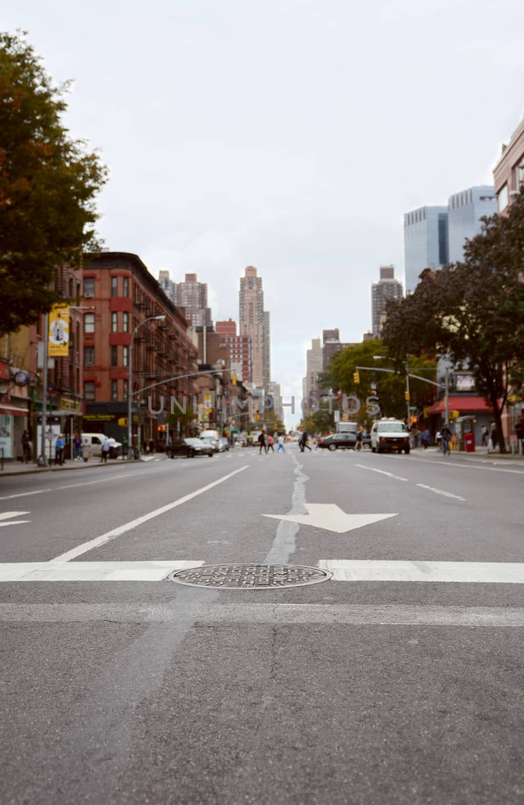 NEW YORK - OCTOBER 23, 2017: 9th Avenue crosswalk, looking north east up the street. Selective focus on manhole cover in road, with Manhattan buildings, traffic and pedestrians beyond.