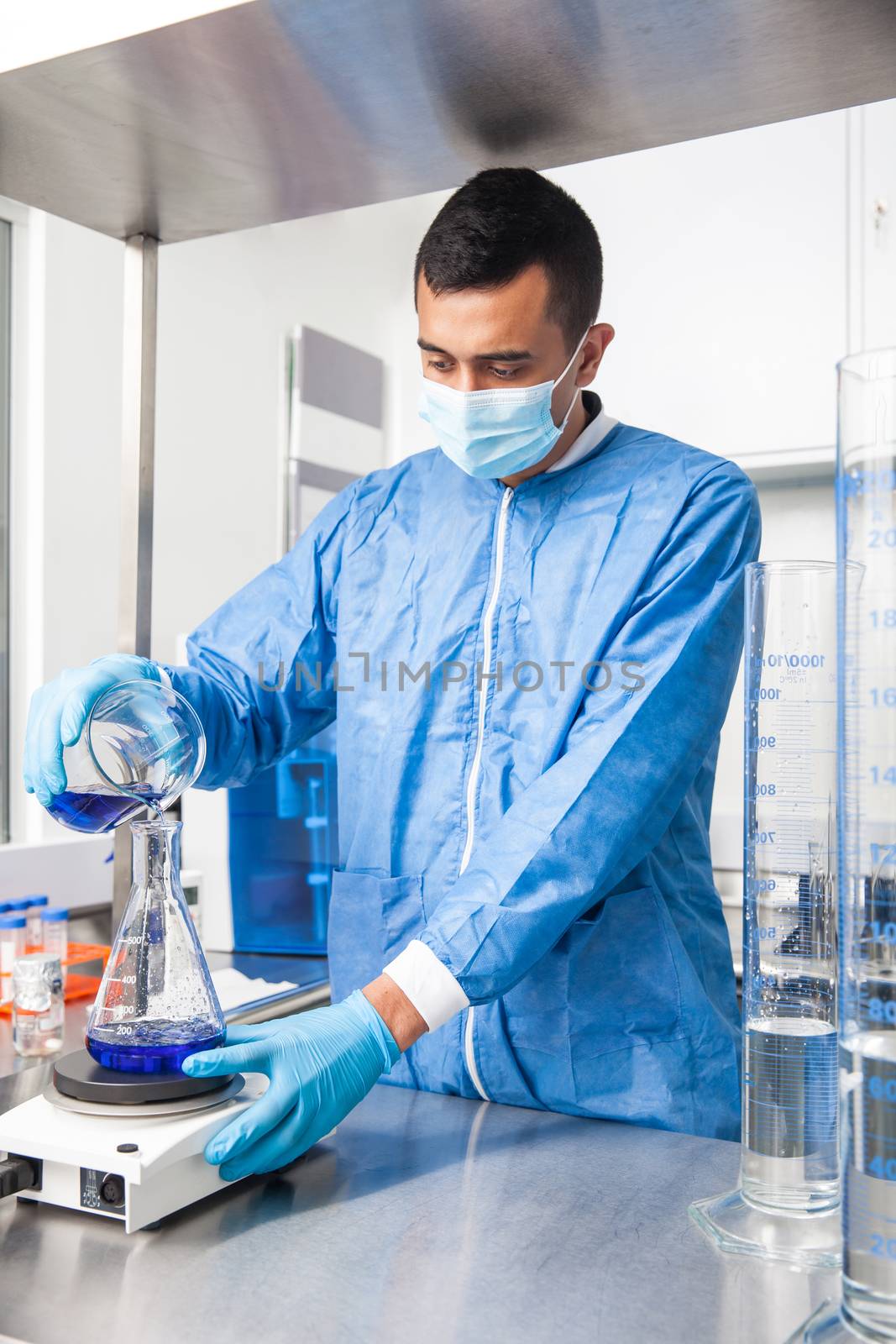 Young male scientist working with an stirrer at laboratory dressed in blue