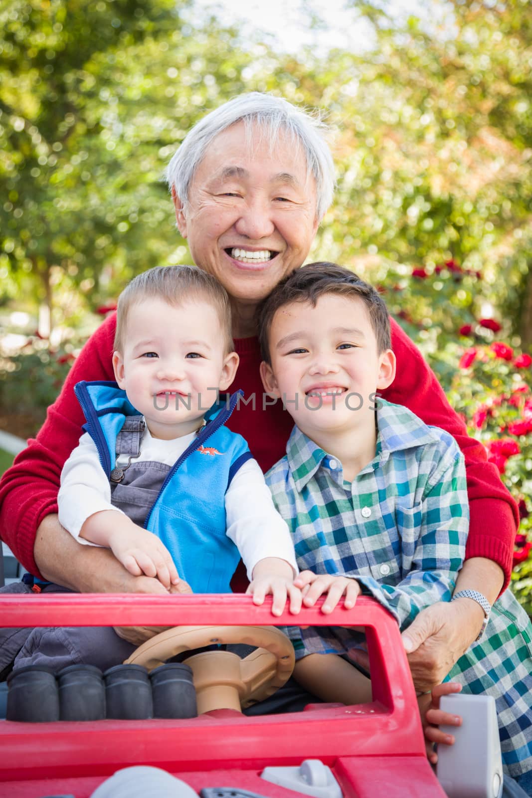 Happy Senior Adult Chinese Man Playing with His Mixed Race Grandchildren by Feverpitched