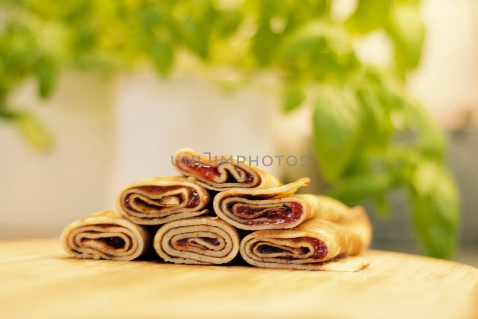 Delicious and fresh pancakes with strawberry sauce on the wooden board in the kitchen.