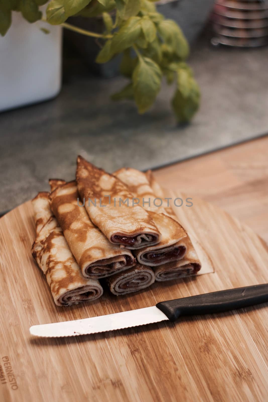 Delicious and fresh pancakes with strawberry sauce on the wooden board in the kitchen.