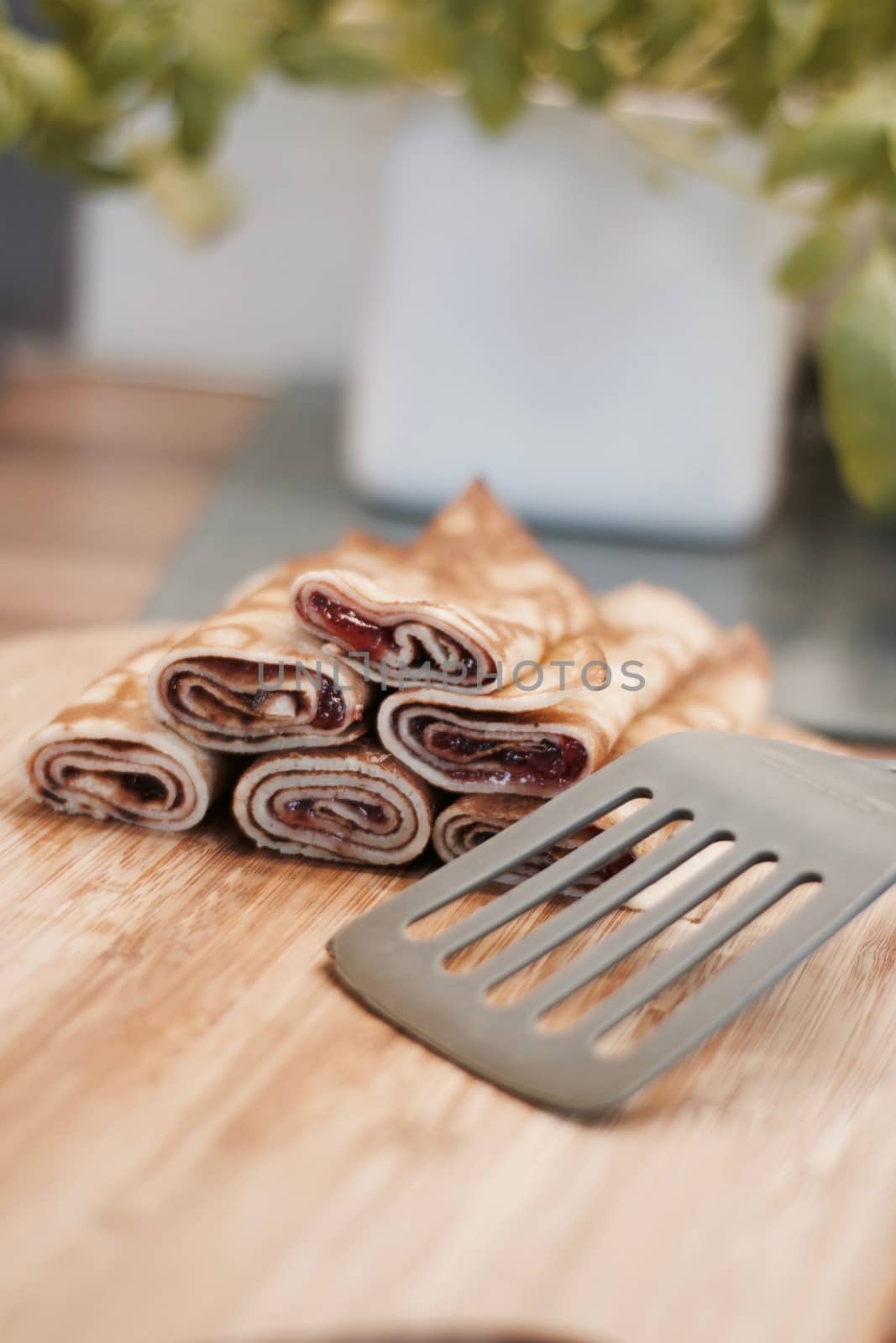 Delicious and fresh pancakes with strawberry sauce on the wooden board in the kitchen.