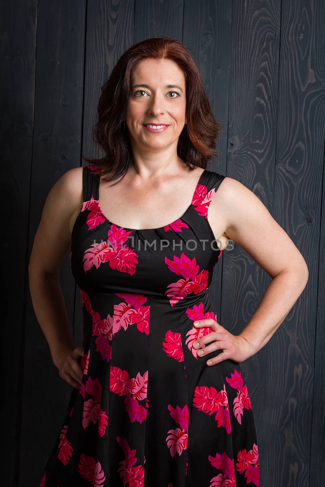 beautiful woman, in her forties, wearing a summer dress in front of a blue stain wood background