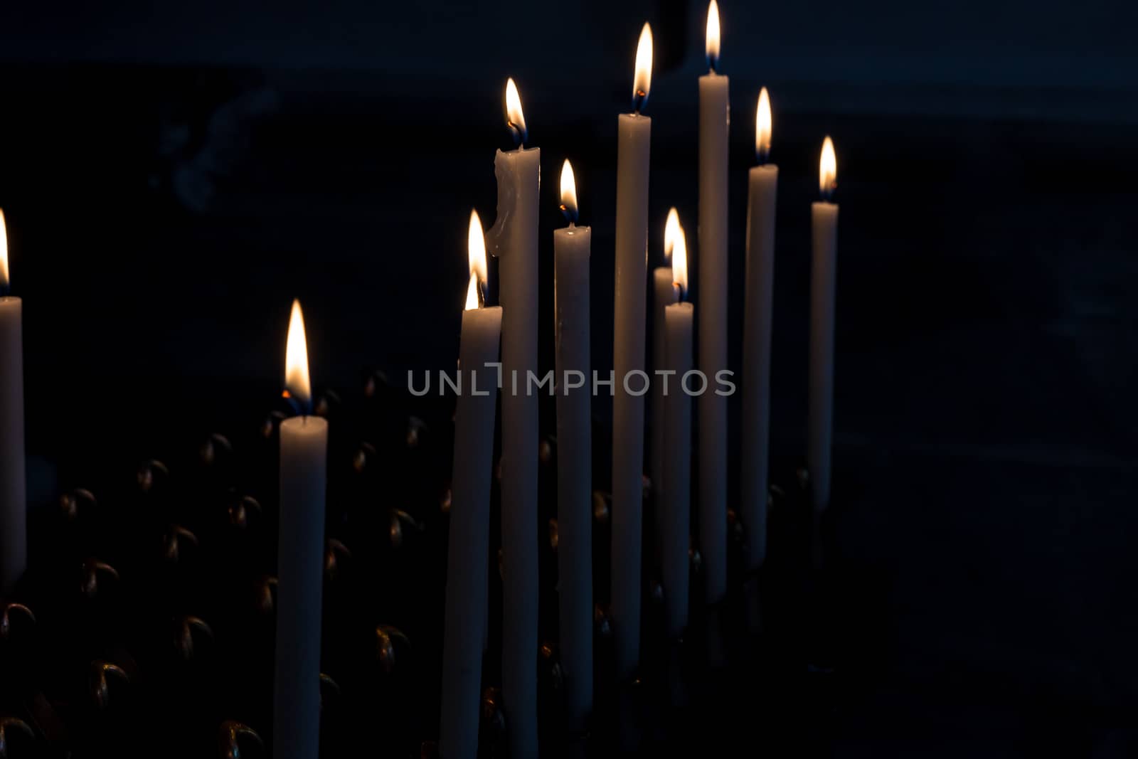 Detail of lit candles in the dark.