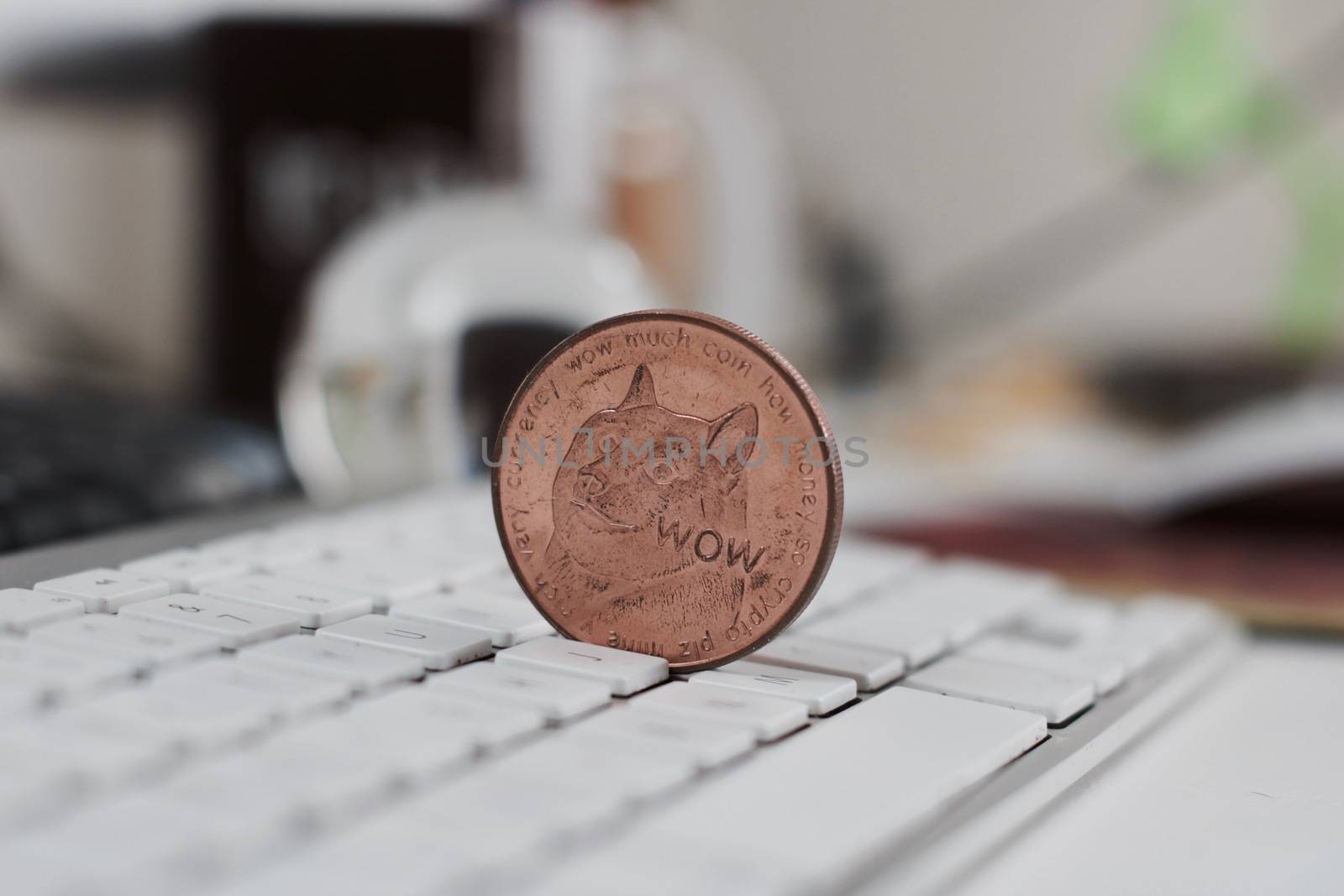 Crypto currency physical brass metal dogecoin coin on the white keyboard in office