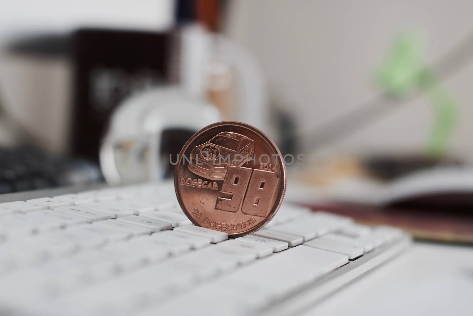 Crypto currency physical brass metal dogecoin coin on the white keyboard in office