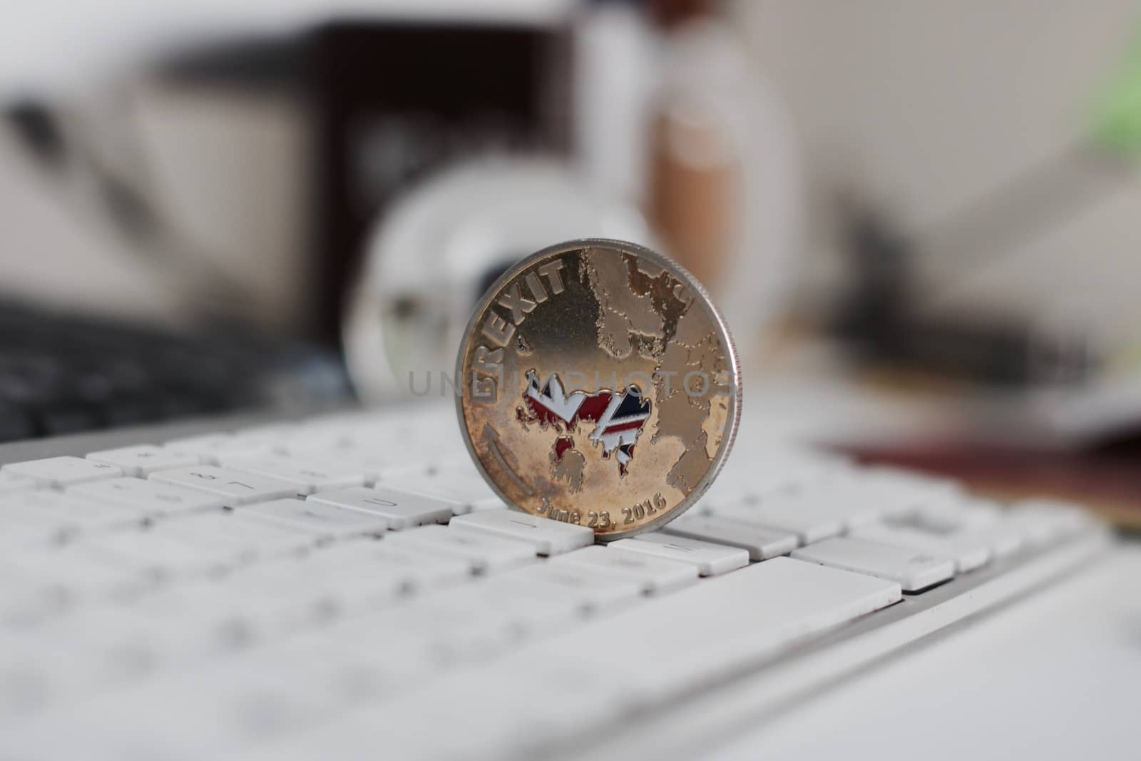 Europe leaving. Gold brexit coin with british map on the white keyboard in office.