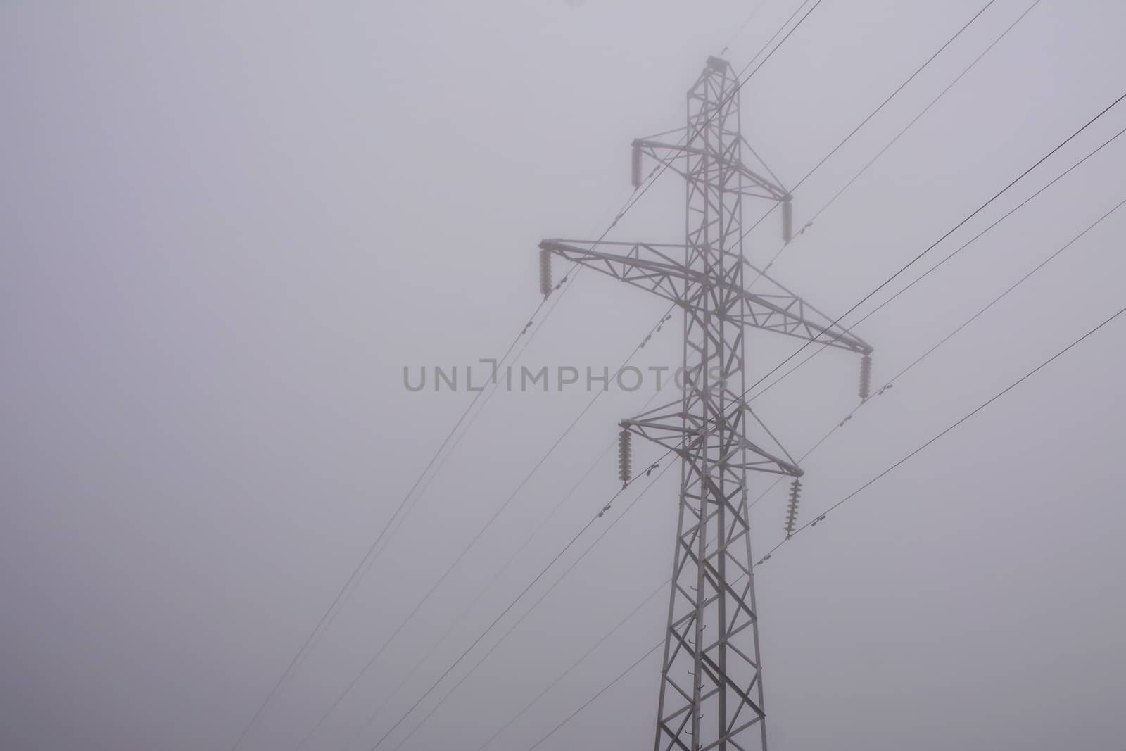 electric pylon and power line in morning fog. Dim world in obscure.