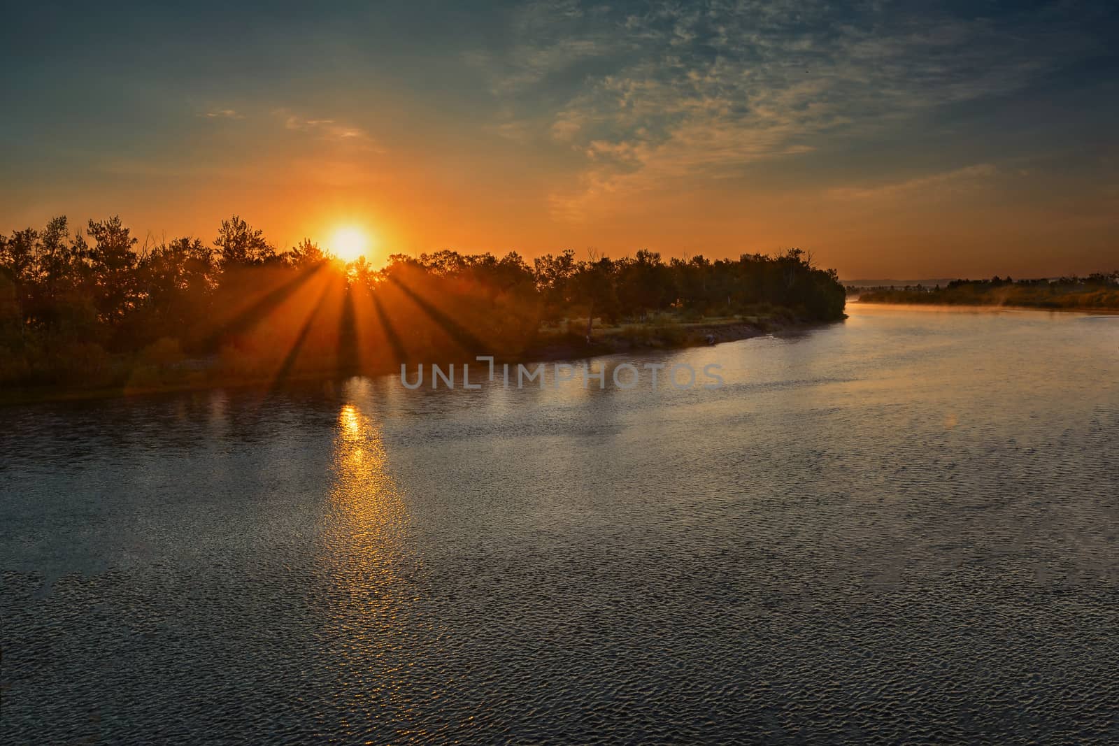 Aerial image showing a sunrise over the water with sunbeams. Beautiful landscape with river and bright sun rays