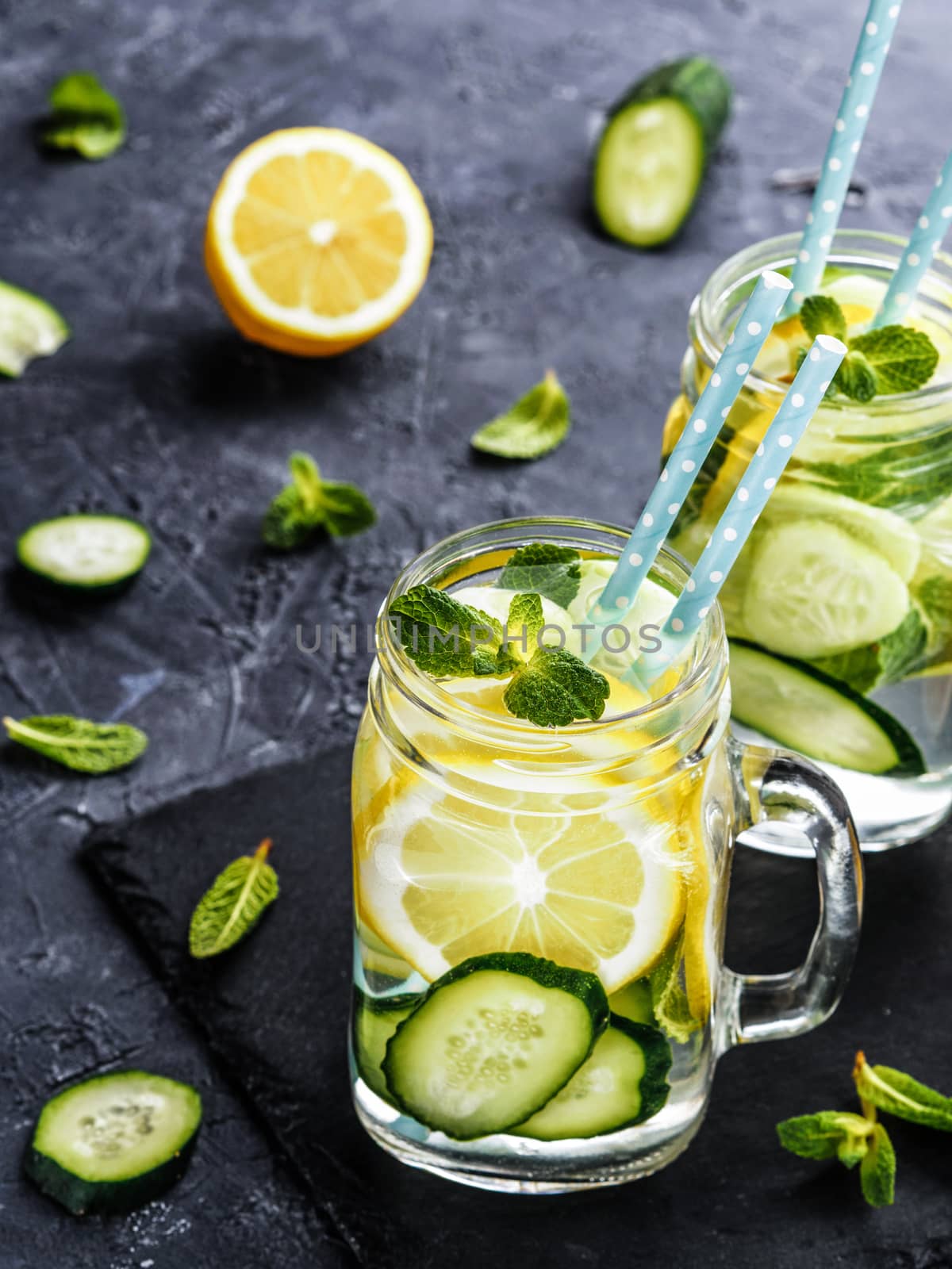 Detox water with cucumber, lemon and mint. Summer drink in mason jar on dark concrete background. Vertical . Copy space
