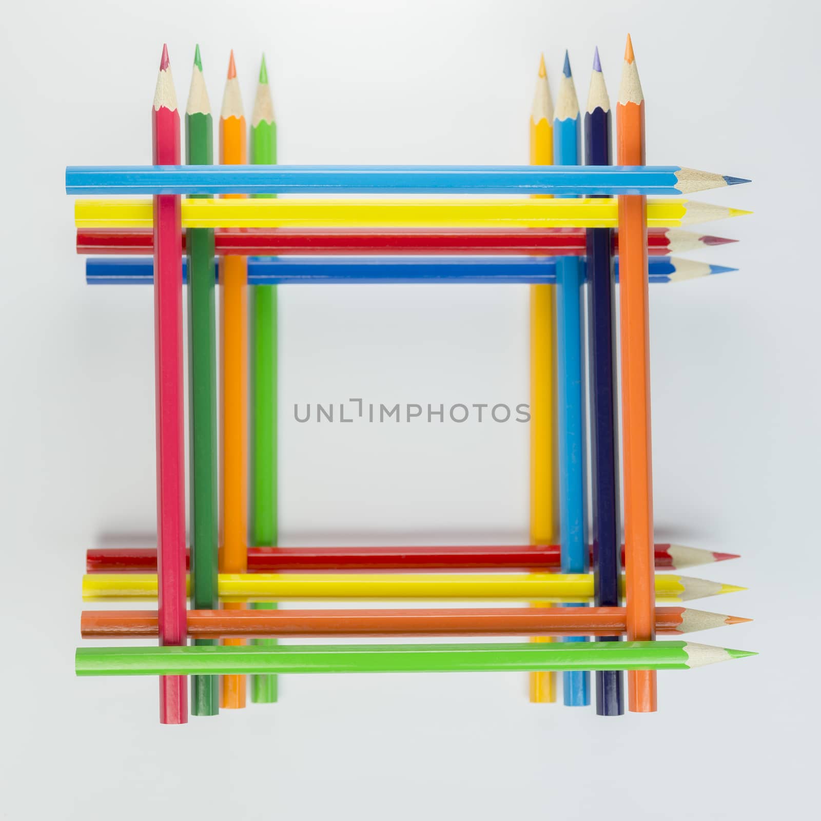 Collection of stacked colored pencils in a square in top view as background picture
