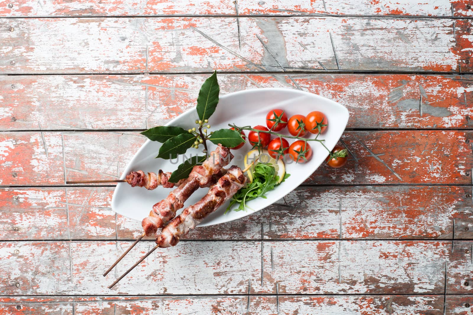 Arrosticini meat in a dish with tomatoes on the table