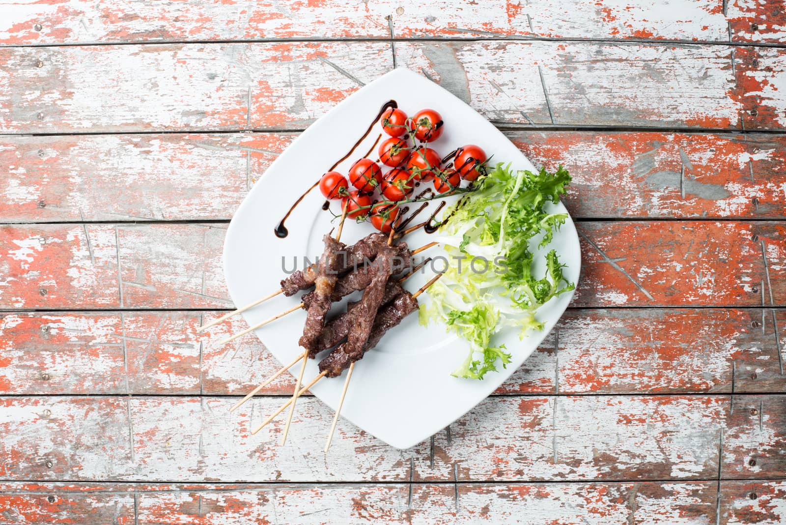 Arrosticini meat in a dish with salad and tomatoes on the table